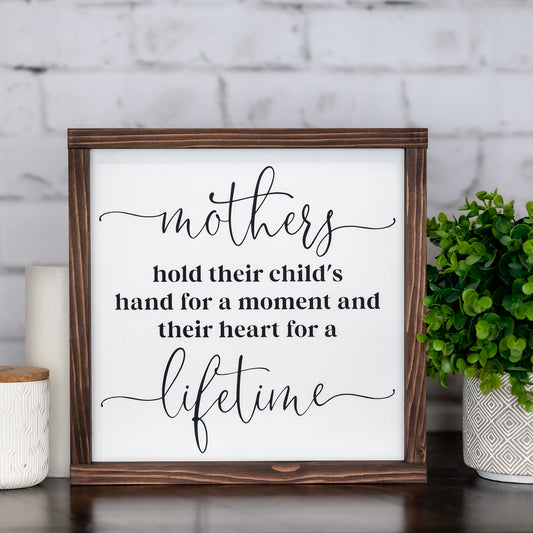 mothers hold their child's hand for a moment and their heart for a lifetime ~ wood sign